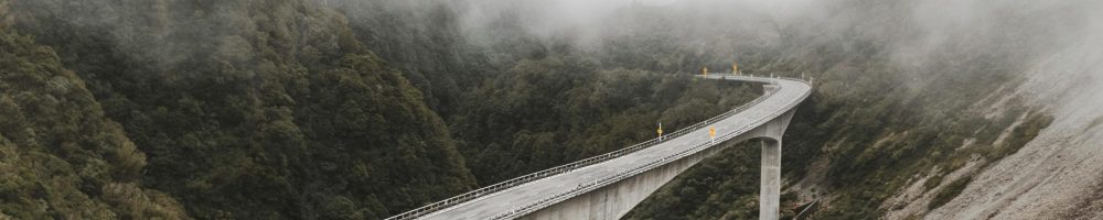 Scenic view of a bridge over a river in a foggy mountain landscape, capturing nature's beauty.