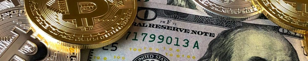 A close-up photo depicting Bitcoin coins on top of US dollar bills, symbolizing finance and cryptocurrency.